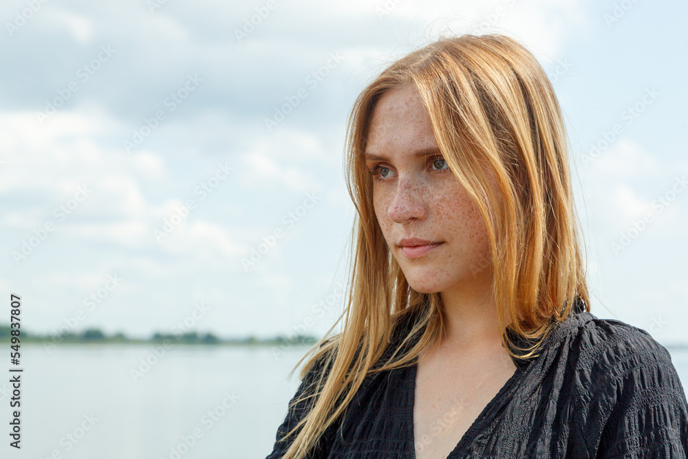 beautiful girl in a black dress on the background of the river, sea with blue sky and clouds beautiful girl in a black dress on the background of the river, sea with blue sky and clouds