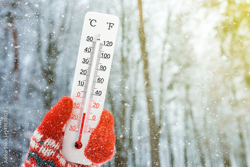 White celsius and fahrenheit scale thermometer in hand. Ambient temperature minus 13 degrees celsius photo