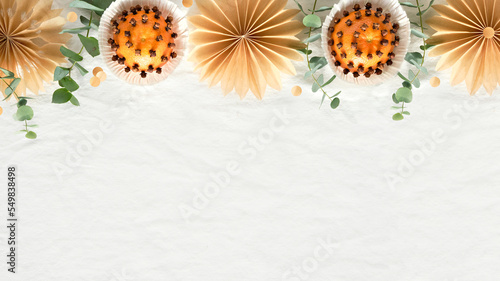 Christmas border  copy-space. Fragrant pomander balls handmade from tangerines with cloves. Handmade stars from brown baking paper. Panoramic flat lay on off white textile tablecloth with eucalyptus.