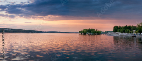 Panoramic view of beautiful lake, island with silhouette of trees under eveni...