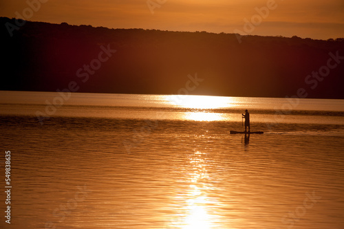 the silhouette of a man on a surfboard in the rays of the setting sun on the ...