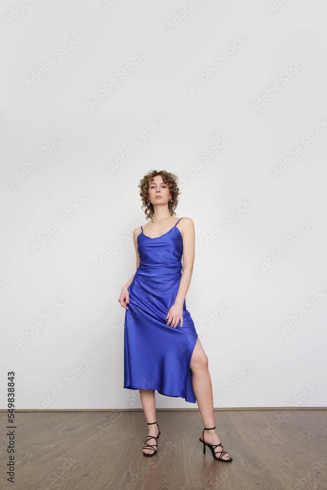 Woman in blue silk satin camisole dress, studio shot. Woman in blue silk satin camisole dress, studio shot.