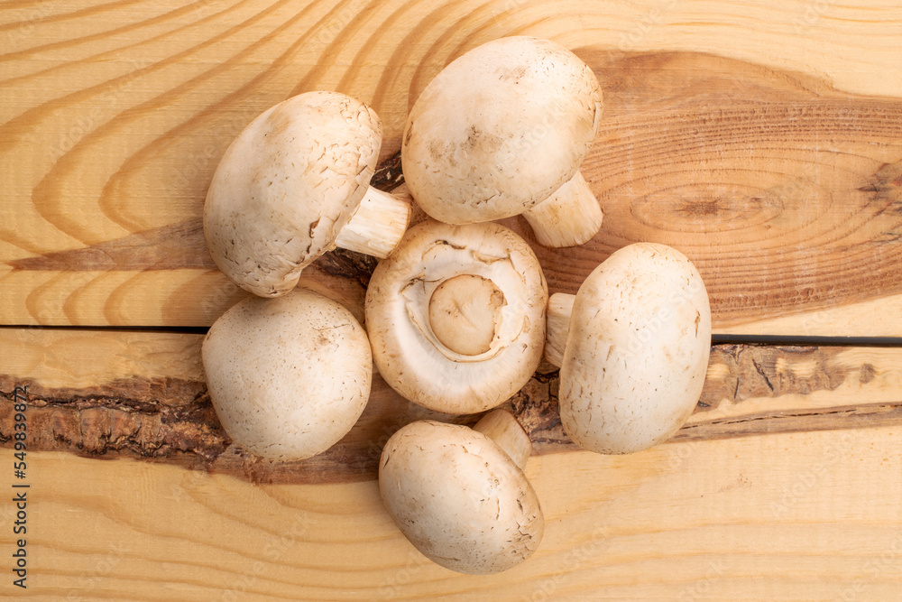 Several whole organic fresh mouth-watering champignon mushrooms, on a table made of natural wood, top view. Several whole organic fresh mouth-watering champignon mushrooms, on a table made of natural wood, top view.