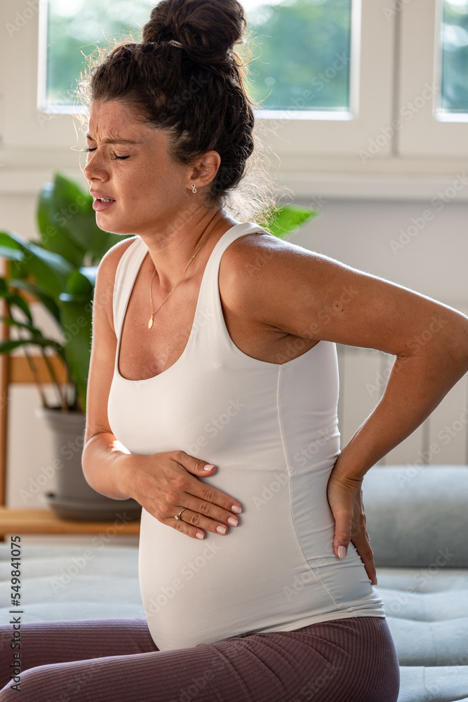 Pregnant woman having back pain while sitting on sofa