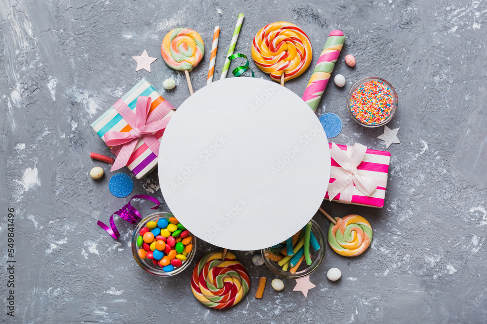 Flat lay holiday composition. Paper blank, lollipop, birthday decorations on Colored background. Top view, copy space for text