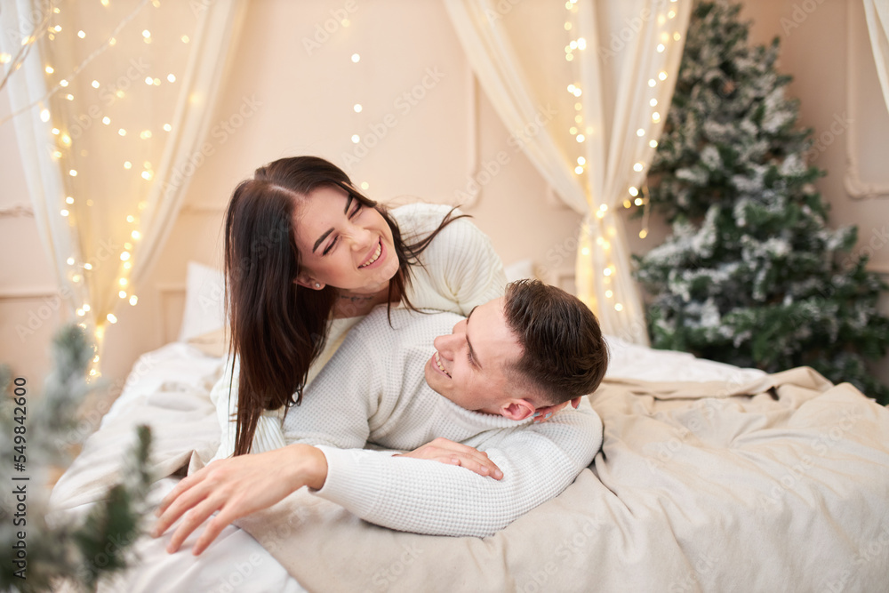 couple in love stands near the Christmas tree and hugs couple in love stands near the Christmas tree and hugs