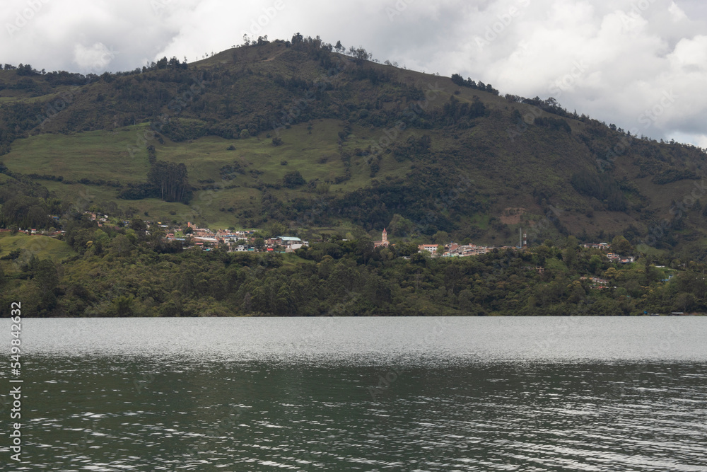 Colombian gachala town viewed from guavio reservoir lake edge with andean mountains in sunny day