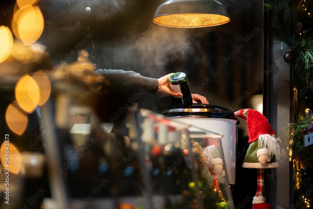 Fototapeta premium Human hand pouring mulled wine into a boiler on a German Christmas market at a stand in Hanover