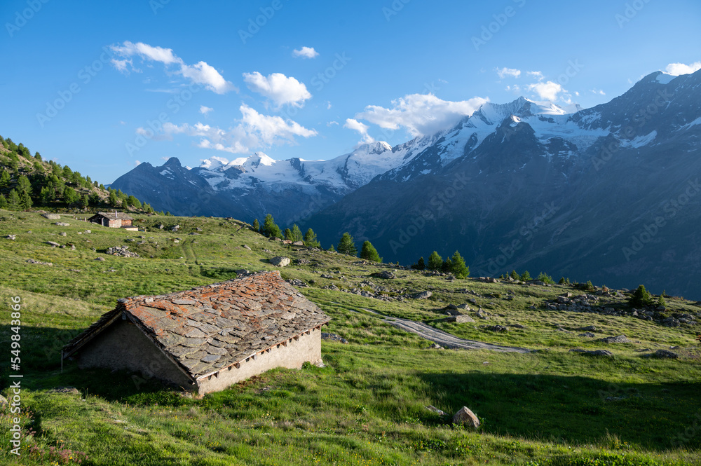 Old alpine hut with stone roof during sunset