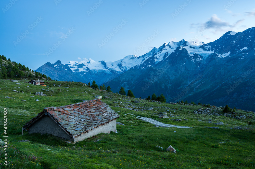 Old alpine hut with stone roof during blue hour