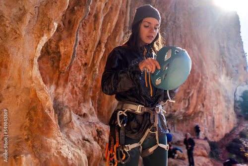 Bilde på lerret Girl, rock climber puts on a helmet on her head.