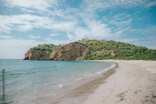 Beautiful beach on a bright sunny day with a forested cliff in the background photo