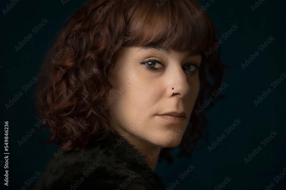 Artistic portrait of a woman with a septum piercing. Close up view of septum piercing, vintage hipster girl portrait smiling. Headshot of woman looking at camera with surgical steel piercing