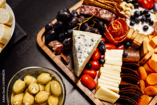 Cheese platter, cheese board meat and board. Vegetables and fruits with cheese and chocolate, prosciutto and salami with bread. Big board of snacks for the party.
