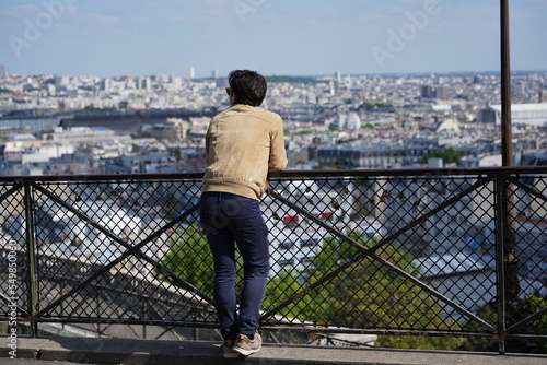 Tableau sur toile Man from rear standing at Montmartre hills and watching city of Paris in distance