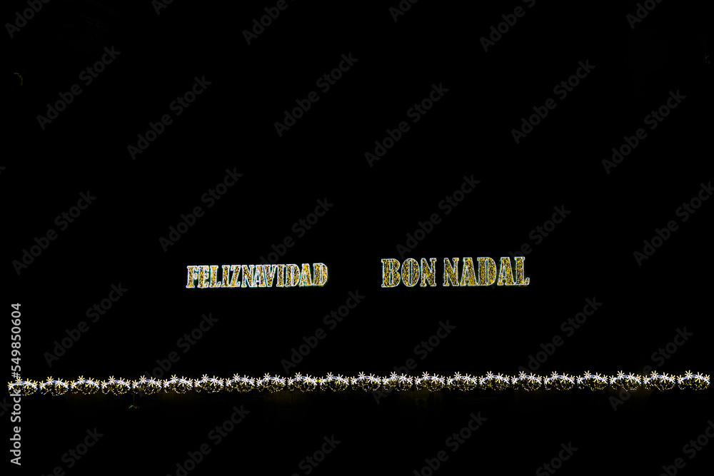 golden shiny neon inscription merry christmas on a black background in Spanish and Catalan, Valencian golden shiny neon inscription merry christmas on a black background in Spanish and Catalan, Valencian