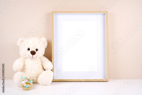 Artwork picture frame product mockup. Baby shower 1st birthday Christening gender neutral party. Styled setting with white teddy bear against a beige and white background. Negative copy space.