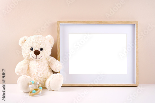 Artwork picture frame product mockup. Baby shower 1st birthday Christening gender neutral party. Styled setting with white teddy bear against a beige and white background. Negative copy space.