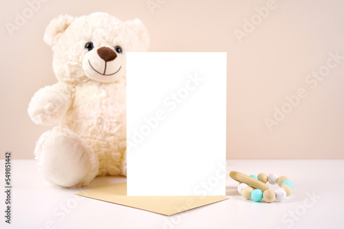 5x7 vertical greeting card party invitation product mockup. Baby shower birthday christening gender neutral. Styled with white teddy bear against a beige and white background. Negative copy space.