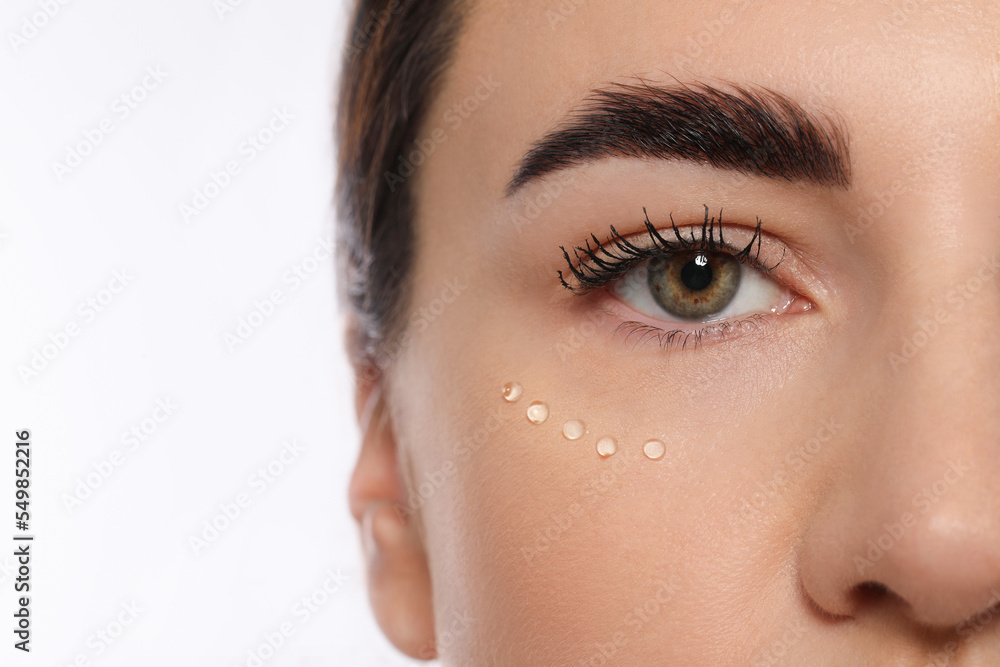 Woman with cosmetic product around eye on white background, closeup. Skin care Woman with cosmetic product around eye on white background, closeup. Skin care