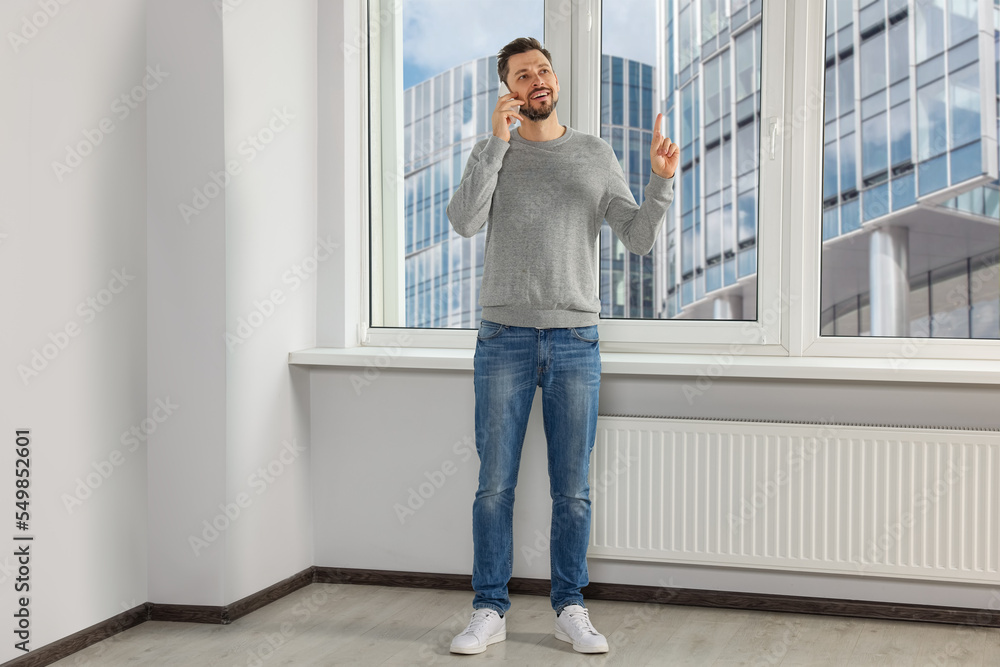 Fototapeta premium Man talking on phone near window indoors