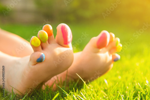 Teenage girl with painted toes on green grass outdoors, closeup © New Africa
