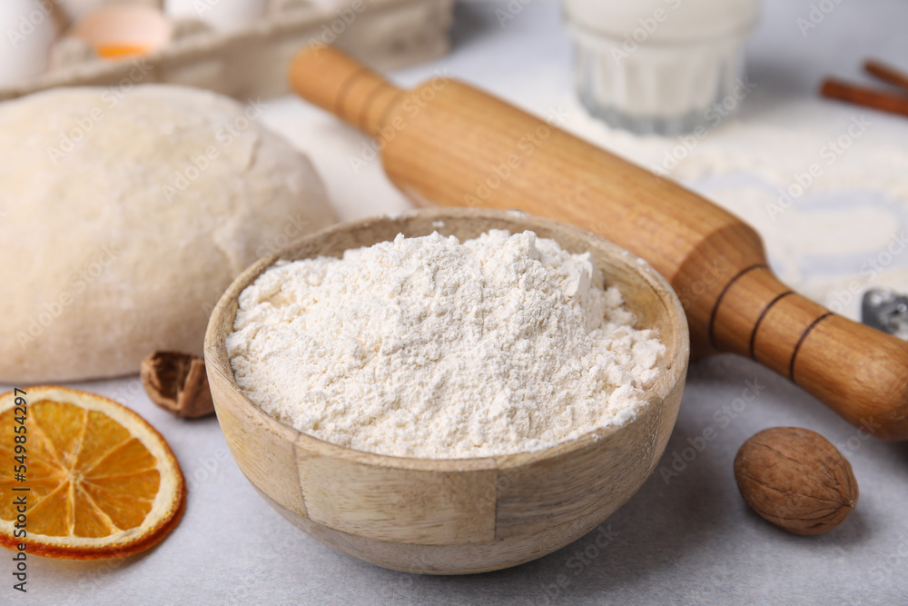 Bowl of flour, rolling pin and ingredients on white table Bowl of flour, rolling pin and ingredients on white table