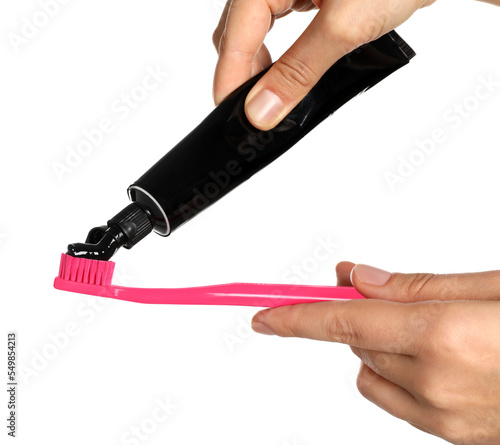 Woman applying charcoal toothpaste on brush against white background  closeup