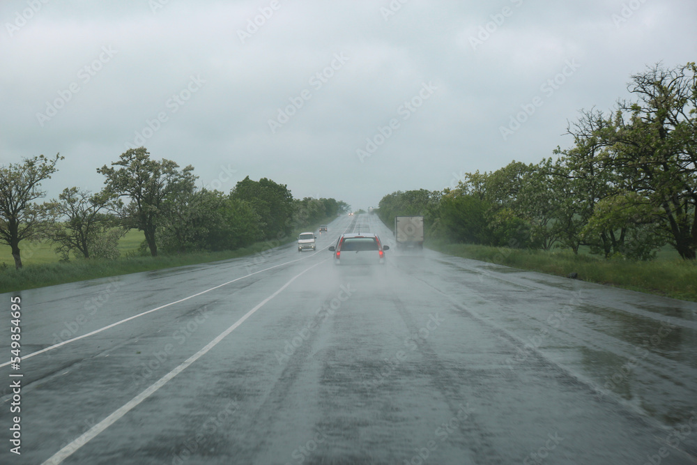 View of country road with cars on rainy day View of country road with cars on rainy day