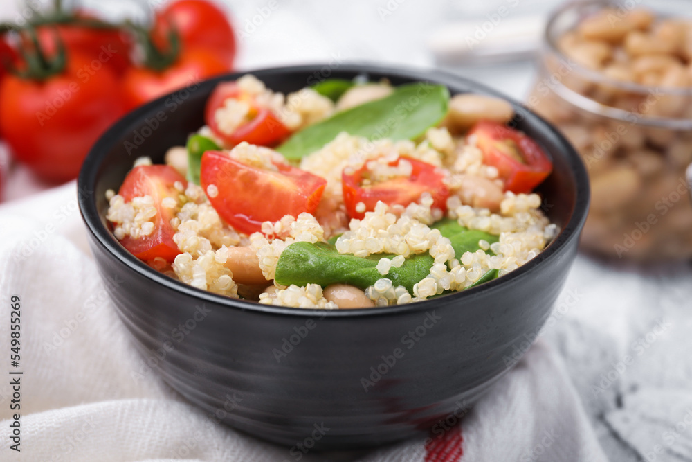 Delicious quinoa salad with tomatoes, beans and spinach leaves served on white table Delicious quinoa salad with tomatoes, beans and spinach leaves served on white table