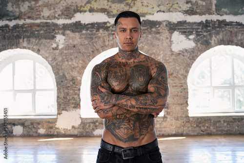 Muscular athletic sexy male with naked torso. Brutal handsome man with tattooed body. Stylish man. A beautiful and charming guy