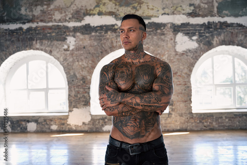 Muscular athletic sexy male with naked torso. Brutal handsome man with tattooed body. Stylish man. A beautiful and charming guy