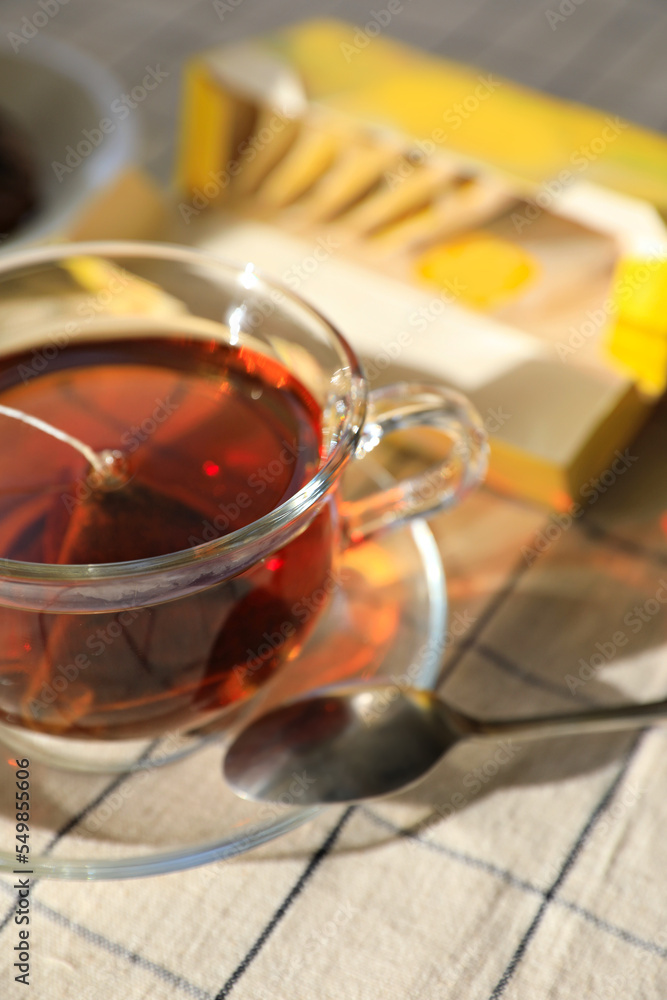 Fototapeta premium Tea bag in glass cup on table, closeup