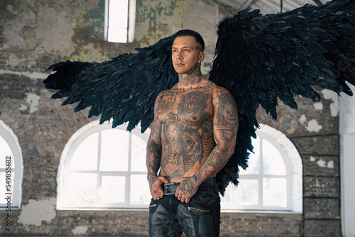  angel man with black wings, stand posing at camera. man fall from heaven, angel with muscular body gained freedom.  tattooed hot man. tattooed black angel. dark angel in leather