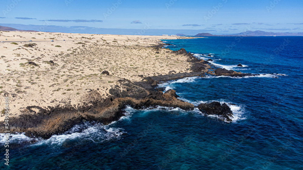 Aerial view of the rocky coastline of the Corralejo Natural Park in the north of Fuerteventura in the Canary Islands, Spain - Desertic barren landscape in the Atlantic Ocean Aerial view of the rocky coastline of the Corralejo Natural Park in the north of Fuerteventura in the Canary Islands, Spain - Desertic barren landscape in the Atlantic Ocean