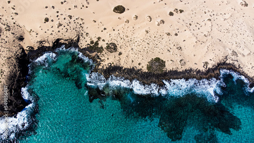 Aerial view of the rocky coastline of the Corralejo Natural Park in the north of Fuerteventura in the Canary Islands, Spain - Desertic barren landscape in the Atlantic Ocean