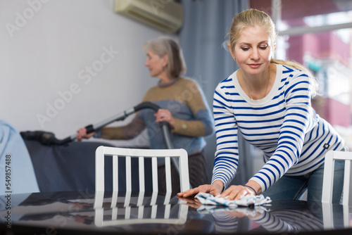 Woman cleaning table with rag at home