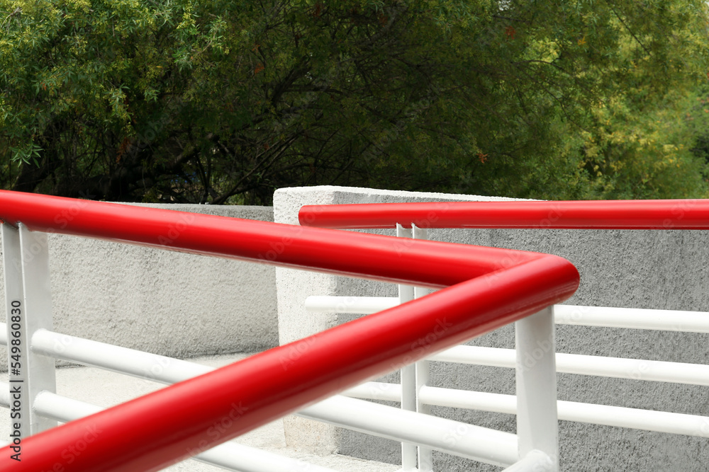 Ramp with red metal handrailings near trees outdoors Ramp with red metal handrailings near trees outdoors