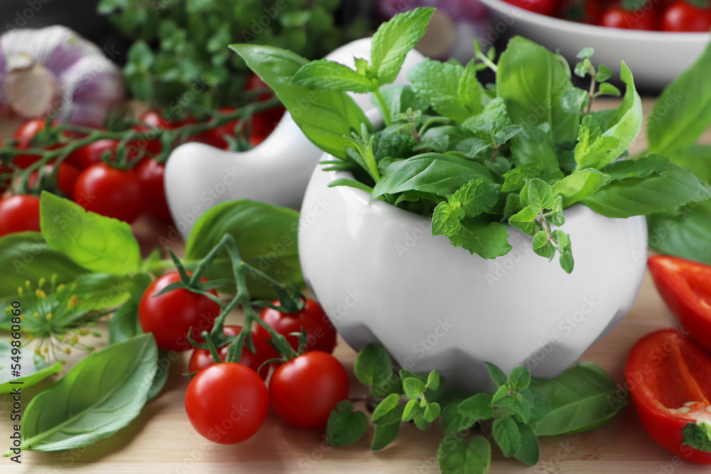 Mortar with fresh herbs, pepper and cherry tomatoes on wooden table, closeup Mortar with fresh herbs, pepper and cherry tomatoes on wooden table, closeup