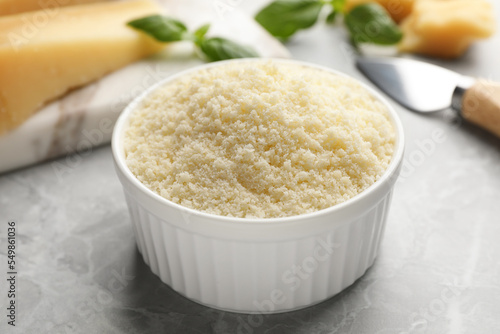 Bowl with grated parmesan cheese on light table, closeup