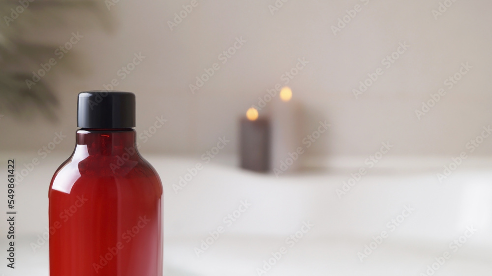 Red bottle of bath foam and candles indoors, closeup. Space for text Red bottle of bath foam and candles indoors, closeup. Space for text