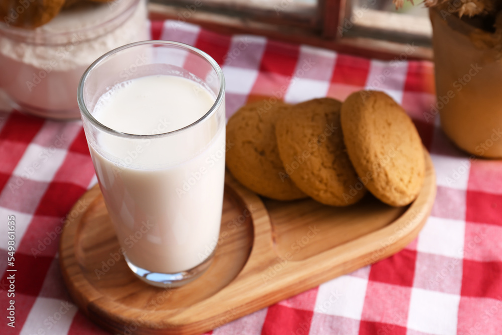 Glass of milk with cookies on red checkered tablecloth, closeup Glass of milk with cookies on red checkered tablecloth, closeup