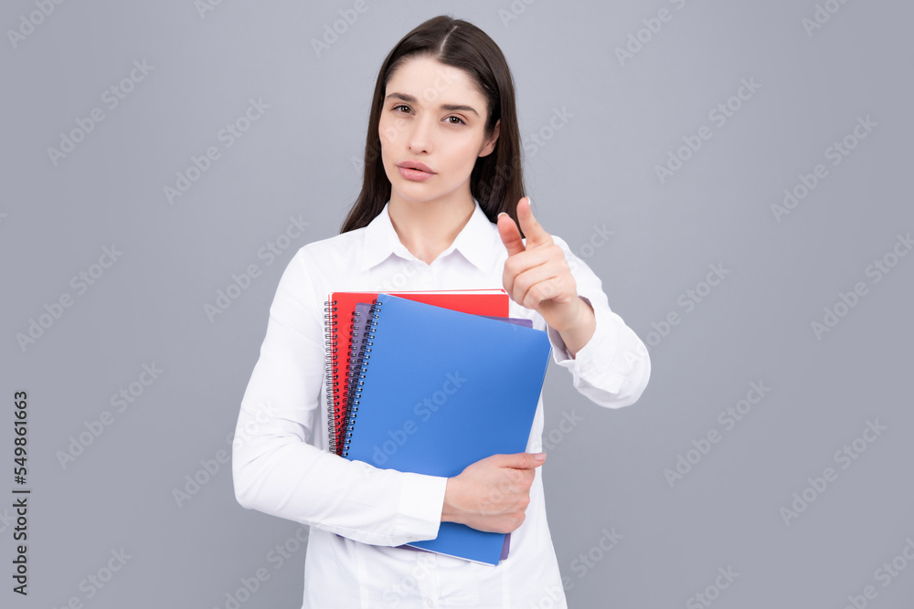 Portrait of student woman. College or high school ducation. Serious woman with notebooks smiling at camera on gray studio background. Young female university student. Portrait of student woman. College or high school ducation. Serious woman with notebooks smiling at camera on gray studio background. Young female university student.