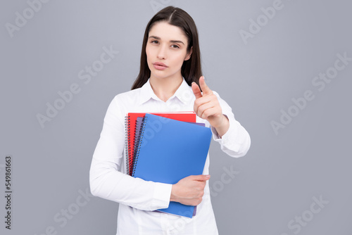 Portrait of student woman. College or high school ducation. Serious woman with notebooks smiling at camera on gray studio background. Young female university student.