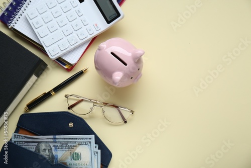 Flat lay composition with piggy bank, glasses and banknotes on beige background. Space for text