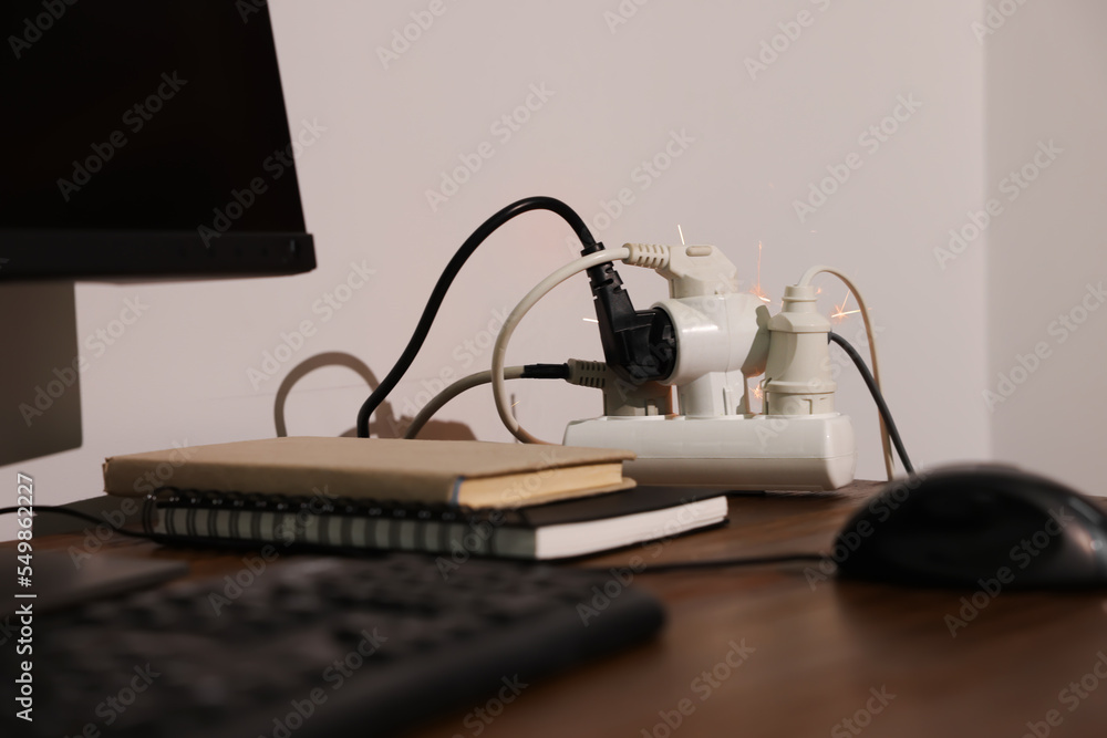 Inflamed plug in power strip indoors on wooden table. Electrical short circuit Inflamed plug in power strip indoors on wooden table. Electrical short circuit