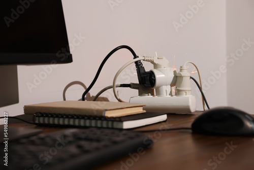 Inflamed plug in power strip indoors on wooden table. Electrical short circuit