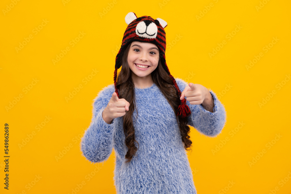 Modern teen girl wearing sweater and knitted hat on isolated yellow background. Happy teenager, positive and smiling emotions of teen girl. Modern teen girl wearing sweater and knitted hat on isolated yellow background. Happy teenager, positive and smiling emotions of teen girl.