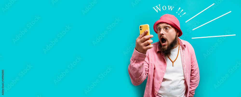 Excited happy young male winner looking at the smartphone feeling joy winning lottery, placing bets, getting cashback online gift isolated. Human face emotions and betting concept. OMG Excited happy young male winner looking at the smartphone feeling joy winning lottery, placing bets, getting cashback online gift isolated. Human face emotions and betting concept. OMG