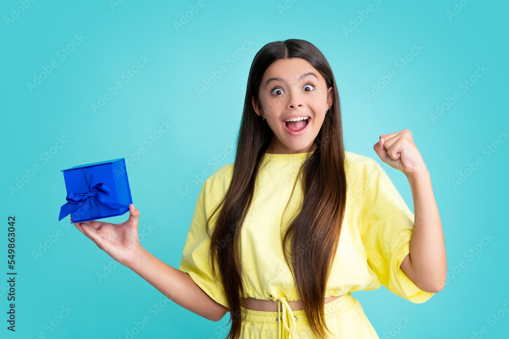 Teenager child with gift box. Present for holidays. Happy birthday, Valentines day, New Year or Christmas. Kid hold present box. Excited face, cheerful emotions of teenager girl. Teenager child with gift box. Present for holidays. Happy birthday, Valentines day, New Year or Christmas. Kid hold present box. Excited face, cheerful emotions of teenager girl.